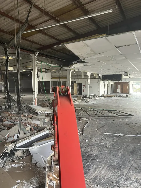Bras rouge de la mini-pelle pendant la dépose des faux plafonds