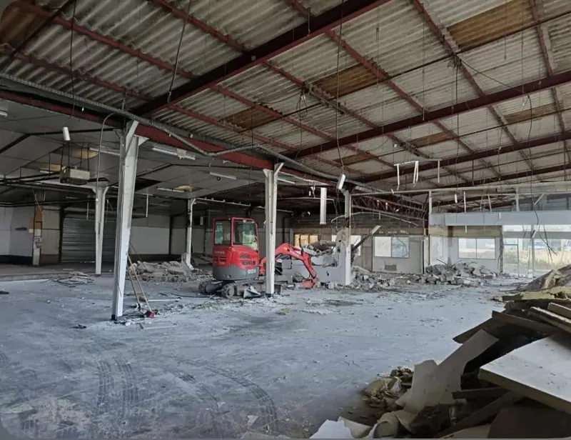 Mini-pelle dans un hangar en cours de curage